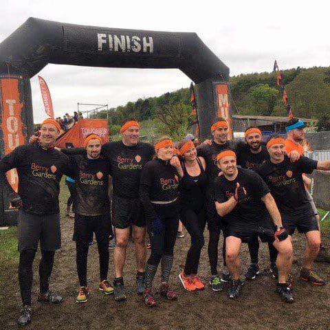 Group of sporty fundraisers all covered in mud.